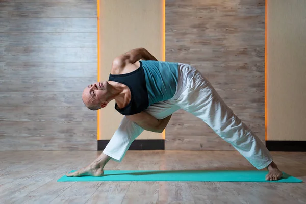 Sportif adam mavi mat yoga yaparken bakan.
