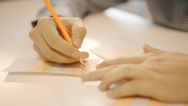 Mans hand fills in a lottery ticket by pencil — Stock Video