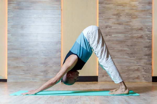 Man står på armar och ben som gör yoga på blå matta. — Stockfoto