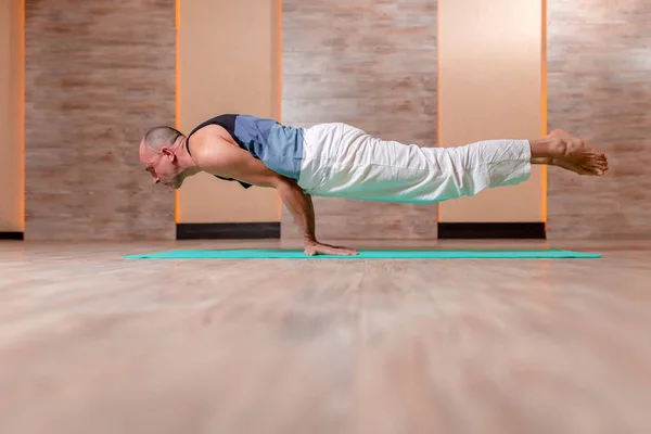 Adult idrottsman man praktiserar yoga stående på händer på blå matta. — Stockfoto