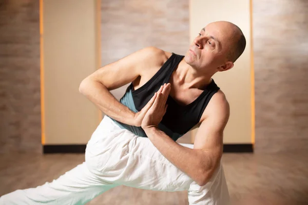 Hombre mirando al costado, practicando yoga de pie sobre alfombra azul . — Foto de Stock