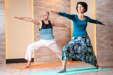 Spor salonunda mavi mat ayakta iken ileri silah ile yetişkin adam ve kadın Yoga pratik.