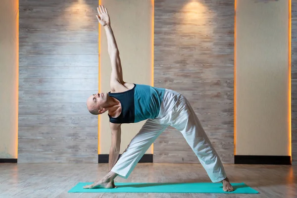 Spor adam mavi mat yoga yapıyor yükseltilmiş kol ile bakıyor. — Stok fotoğraf