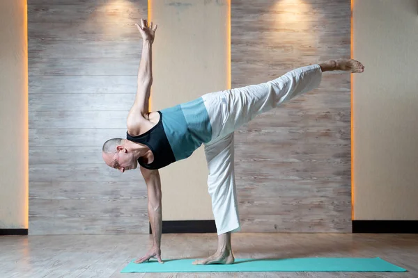 Atletik adam ayakta bacak mavi mat yoga yapıyor. — Stok fotoğraf
