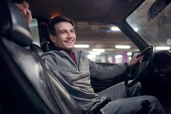 Image de côté de l'homme heureux regardant la caméra assise dans la voiture . — Photo