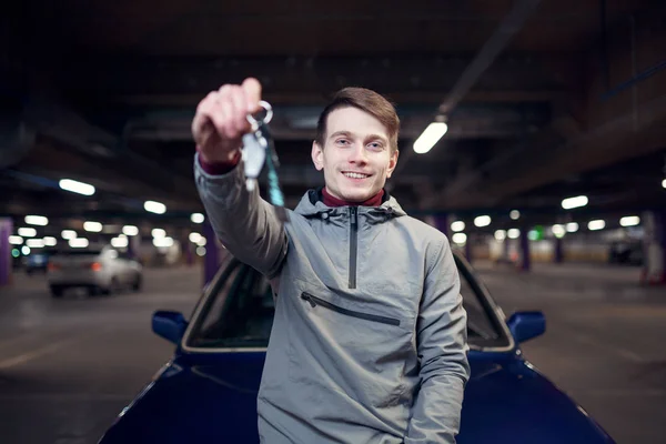 Gambar pria dengan kunci berdiri di samping mobil di tempat parkir bawah tanah — Stok Foto