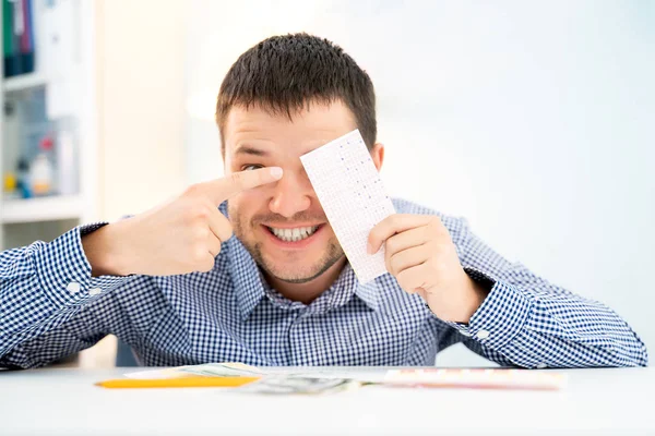 Foto eines glücklichen Mannes mit Lottoschein am Tisch. — Stockfoto