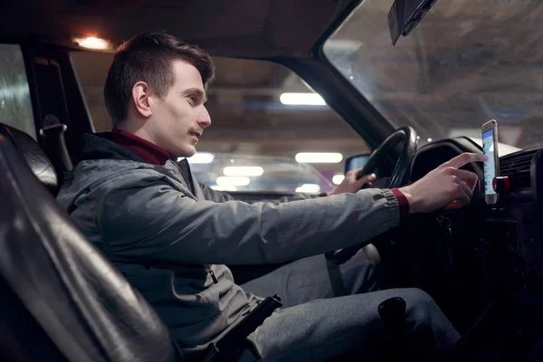 Side photo of male driver setting up navigator while sitting in car . — Stock Photo, Image