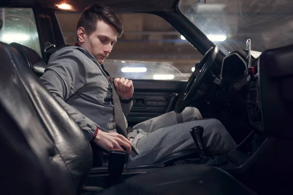 Side photo of male driver fastening seat belt while sitting in car . — Stock Photo, Image