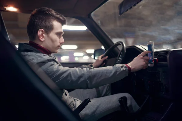 Side photo of man driver setting up navigator while sitting in car. — Stock Photo, Image