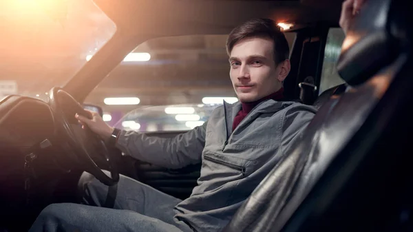 Zdjęcie z boku człowieka patrząc na aparat siedzi w samochodzie na podziemne ubezpieczenie — Zdjęcie stockowe