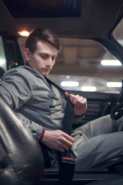 Photo de côté de l'homme conducteur attachant la ceinture de sécurité tout en étant assis dans la voiture sur l'assurance souterraine — Photo