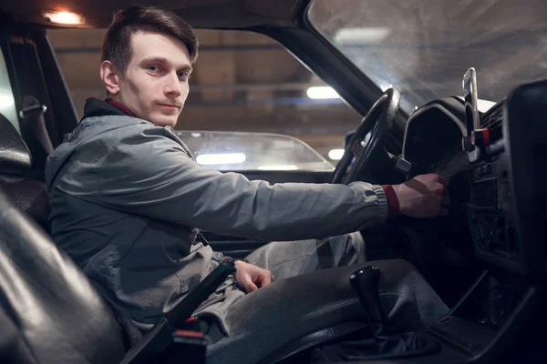 Zdjęcie z boku człowieka patrząc na aparat siedzi w samochodzie — Zdjęcie stockowe