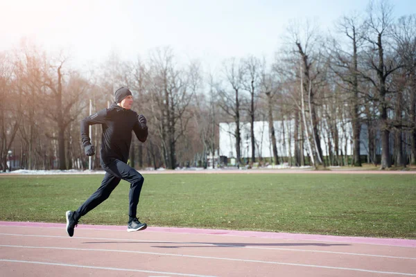 运动男子在春季慢跑时穿过体育场的照片 — 图库照片