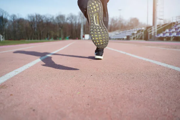 Image from back of legs of athlete running through stadium — Stock Photo, Image