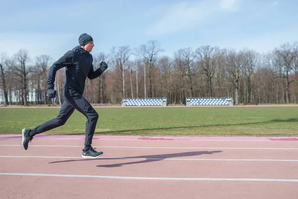 Foto op de zijkant van atleet man loopt door Stadion tijdens de lente JOG — Stockfoto