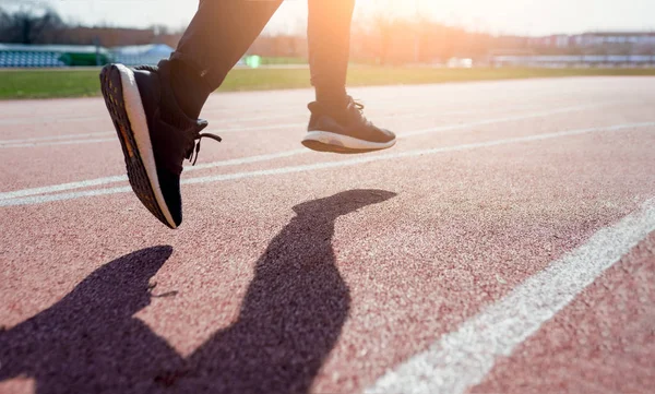 Photo from side close-up of athletes feet running around stadium — Stock Photo, Image