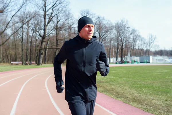 Foto eines jungen Athleten, der beim Frühjahrsjoggen durch das Stadion läuft . — Stockfoto