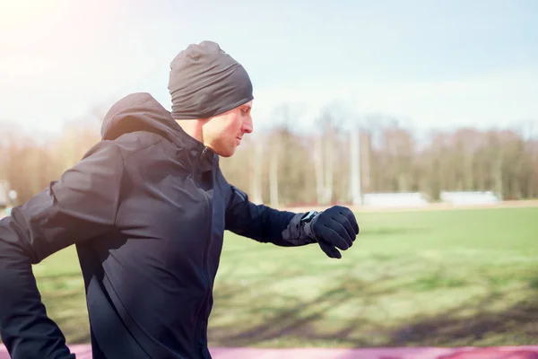 Side photo of running man in black clothes on spring afternoon. — Stock Photo, Image