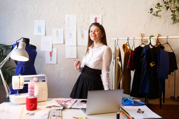 Photo of happy seamstress woman standing next to mannequin.