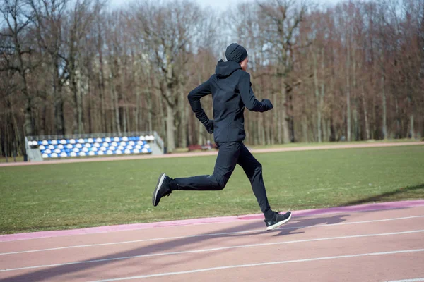 Foto an der Seite eines Sportlers, der beim Frühjahrsjoggen durch das Stadion läuft — Stockfoto