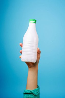 Mavi arka plana karşı elinde plastik şişe.