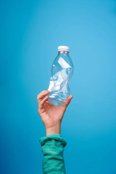 Garrafa de plástico na mão contra fundo azul . — Fotografia de Stock