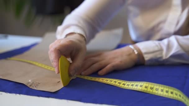 Gros plan sur les mains d'un tailleur féminin dessin gabarit sur tissu — Video