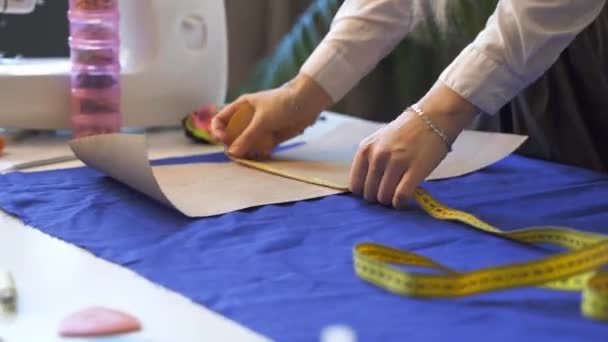 Gros plan sur les mains d'un tailleur féminin dessin gabarit sur tissu — Video