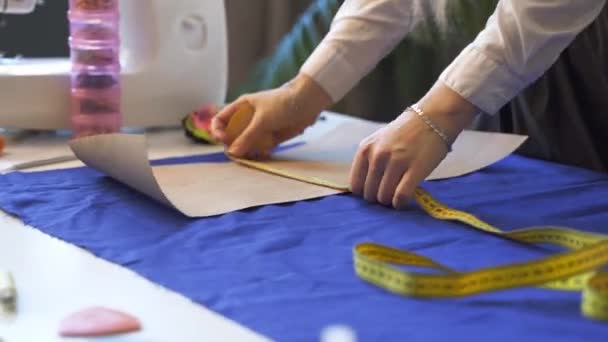 Close up on hands of a female tailor drawing template on fabric — Stock Video