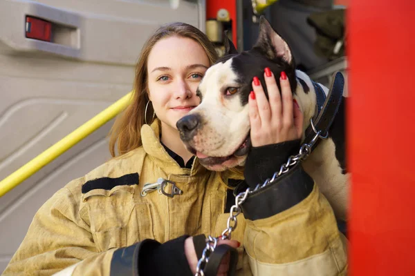 Gambar wanita api bahagia dengan anjing berdiri di dekat truk pemadam kebakaran — Stok Foto
