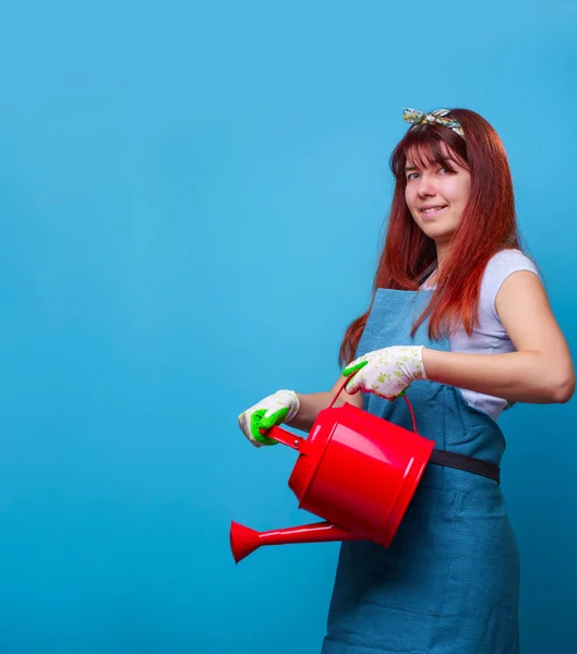 Foto de florista femenina feliz con una regadera en sus manos sobre fondo azul vacío . — Foto de Stock