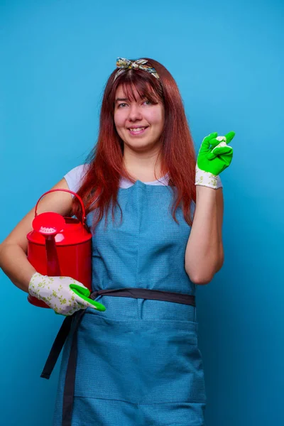 Photo of happy female florist with watering can in hands of pointing finger to side — Stock Photo, Image