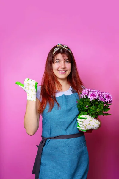 Photo of cheerful girl with chrysanthemum pointing hand to side — Stock Photo, Image