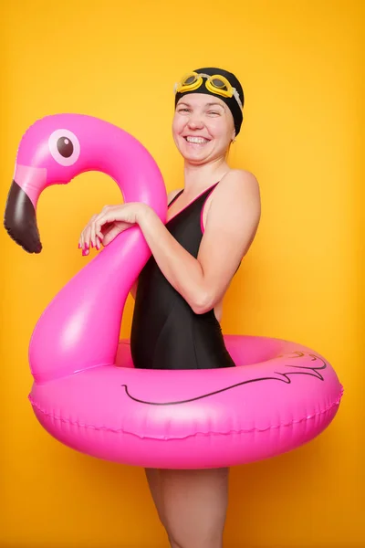 Foto van de vrouw in zwarte badpak met Flamingo reddingsboei op lege oranje achtergrond — Stockfoto