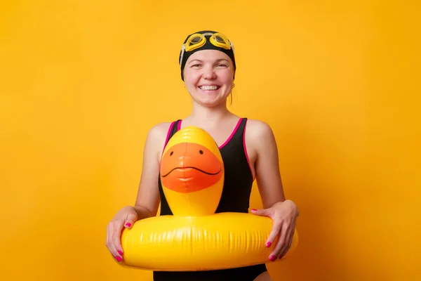Image of smiling girl in bathing suit with lifebuoy on empty orange background — Stock Photo, Image