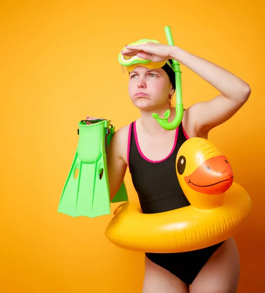 Foto de mujer con aletas en las manos, máscara de natación y con salvavidas sobre fondo naranja vacío — Foto de Stock