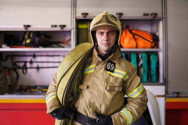 Фото пожарного в шлеме на фоне пожарной машины — стоковое фото