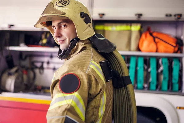 Образ чоловіка пожежника в шоломі на тлі пожежної машини — стокове фото
