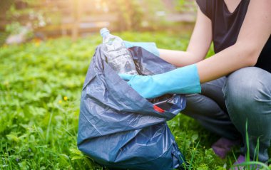 Çim kirli plastik şişe toplama lastik eldiven kadın resmi