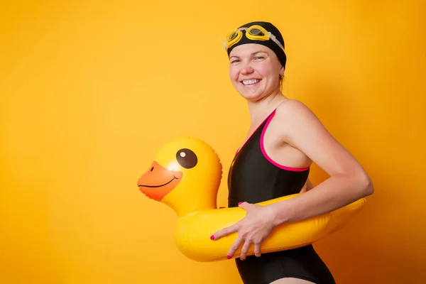 Afbeelding van lachende vrouw in badpak met reddingsboei op lege oranje achtergrond — Stockfoto