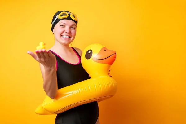 Photo of happy woman in bathing suit with lifebuoy on empty orange background — Stock Photo, Image