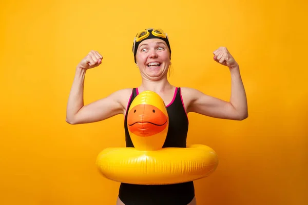 Image of strong woman in swimsuit with life preserver on empty orange background — Stock Photo, Image