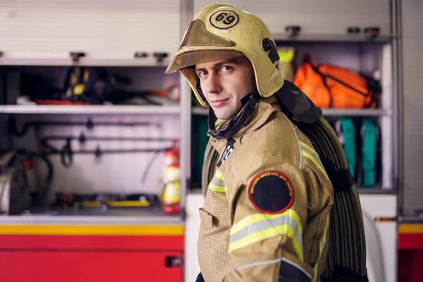 Imagem do homem bombeiro no capacete no fundo do caminhão de bombeiros — Fotografia de Stock