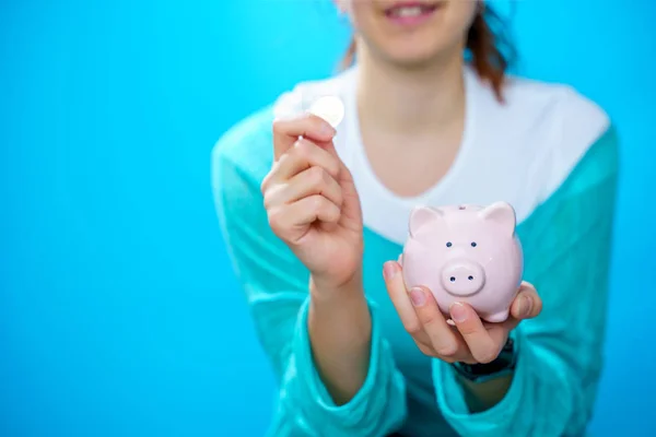 돼지 저금통에 돼지를 넣는 행복한 여성의 이미지 — 스톡 사진