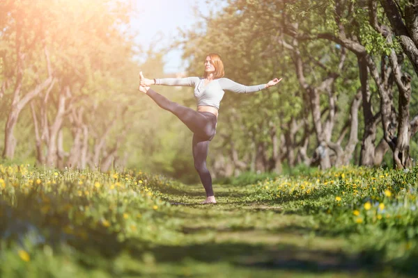 Φωτογραφία της γυναίκας που κοιτάζει στην πλευρά του στέκεται στο ένα πόδι εξάσκηση γιόγκα στο δάσος κατά τη διάρκεια της ημέρας — Φωτογραφία Αρχείου