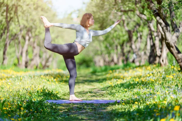 Ormanda mavi halı üzerinde duran yoga yapan kadın resmi — Stok fotoğraf