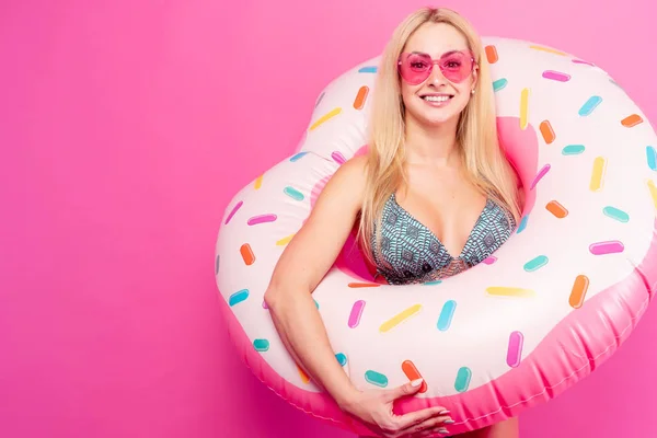Foto de chica rubia feliz en gafas de sol de traje de baño con rosquilla inflable para nadar — Foto de Stock
