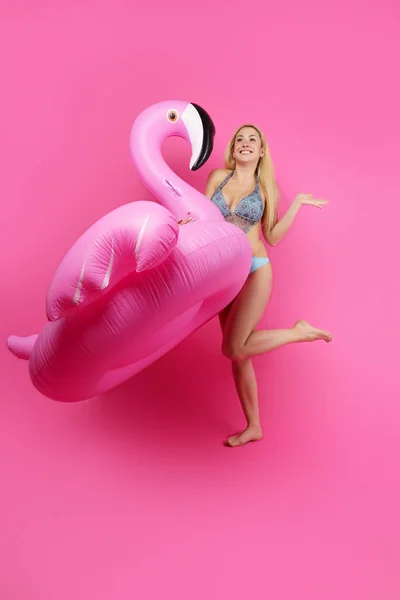 Full-length photo of blonde in bathing suit and pink glasses with pink inflatable flamingo on empty pink background — Stock Photo, Image