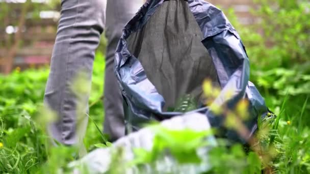 Person plockar upp sopor sätter flaska i SOP påse i parken — Stockvideo